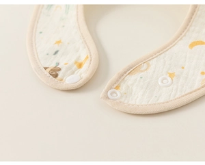 Close-up of white plastic snap button and soft cotton muslin fabric on baby bib