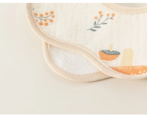 Close-up of cotton gauze baby bib with mushroom and berry pattern and soft texture