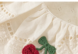 Close-up of girls' cotton shirt with lace collar and crochet cherry applique detail