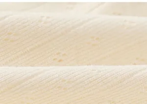 Close-up of soft light beige pointelle knit fabric showing delicate hollow patterns