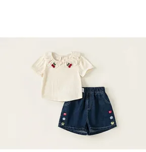 Detailed view of beige knit top with lace collar and denim shorts with apple design
