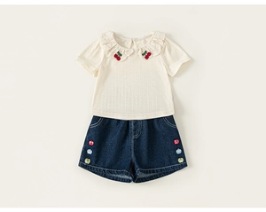 Detail of girl's summer set with cherry embroidery and lace collar on cream top
