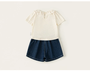 Detailed close-up of girls beige short-sleeve shirt with lace collar and denim shorts
