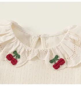 Close-up of lace collar with cherry embroidery on breathable pointelle knit baby shirt