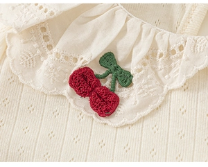 Detailed macro view of cherry embroidery and delicate lace collar on a knit t-shirt