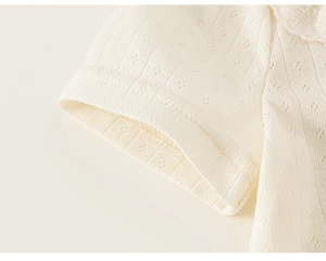 Close-up of cream knit t-shirt sleeve with delicate pointelle pattern and lace trim