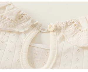 Detailed macro view of the pointelle knit fabric and lace ruffle collar with button closure