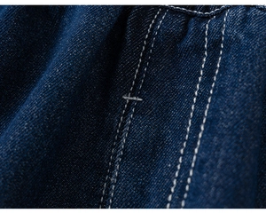 Detailed macro view of navy denim fabric featuring contrast white triple stitching