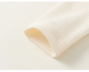 Vue détaillée macro de la texture du tissu côtelé crème et de l'ourlet de la robe enfant