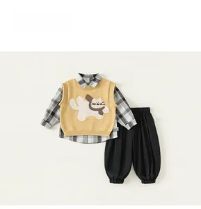 Vista piatta di gilet in maglia gialla con gatto, camicia a quadri e pantaloni neri