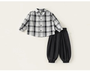 Dettaglio del set da bambino con camicia a quadri a maniche lunghe e pantaloni neri comodi