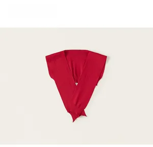 Detailed view of red knitted children's shawl with ribbed edges on a beige background