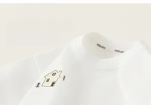 Close-up of white cotton children's t-shirt with round neck and cartoon house print