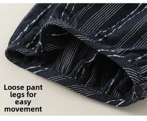 Detail view of dark blue striped trousers with loose cuffs and cotton-linen texture