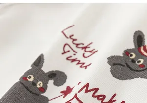 Macro detail of soft white fabric with grey rabbit print and Lucky Time text for kids set