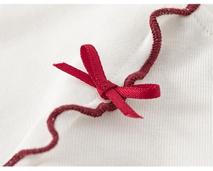 Close-up of ribbed knit fabric with red bow detail and scalloped wavy edges on kids outfit