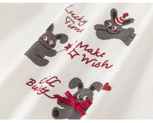 Detail of white cotton knit fabric with bunny print and red silk bow on girls' outfit