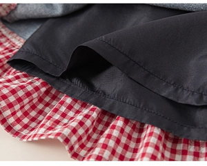 Detail of girls' skirt showing denim stitching with red gingham ruffled hem and lining