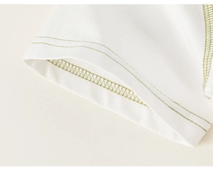 Detailed close-up of white fabric with olive green contrast stitching and double-needle hem