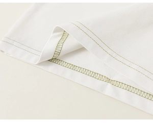 Detail of white cotton T-shirt featuring contrast olive green stitching on the hemline