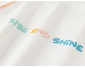 Detail of Rise and Shine colorful typography on white cotton kids T-shirt with orange stitching