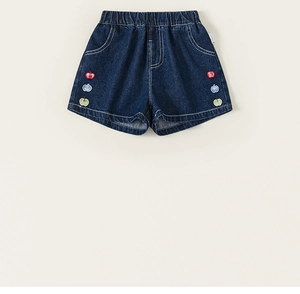 Gros plan détaillé du short en denim bleu foncé avec trois écussons pomme colorés