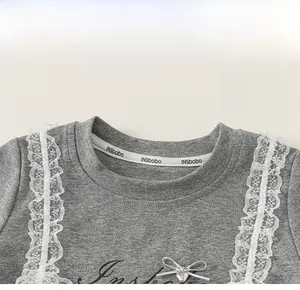 Detail of grey short sleeve tee with white lace ruffles and silver bow decoration