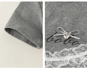 Detail of grey girl's T-shirt with lace trim, silver ribbon bow and heart pendant charm