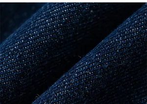 Détail macro du tissu denim bleu foncé montrant la texture sergée et le fini coton