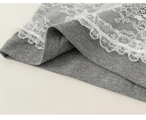 Detail of grey shirt hem featuring delicate white floral lace layers and stitching