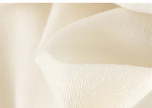 Vue macro montrant la texture douce et le tissage du tissu floral en coton blanc cassé