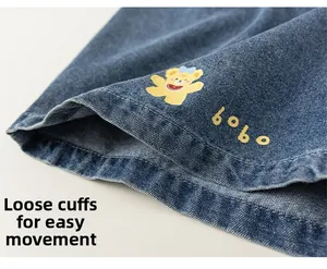 Detail of blue denim shorts featuring a cute yellow bear print and embroidered bobo text