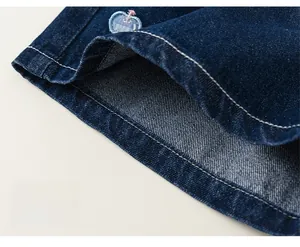 Détail de l'ourlet du short en jean ample avec une jolie petite broderie de pomme