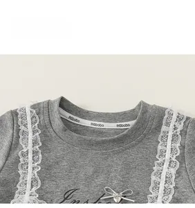 Detail of grey girl's T-shirt with lace trim and silver heart pendant bow