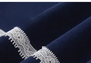 Detail of navy blue knit fabric with delicate white lace trim on a girl's shirt