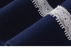 Close-up of navy blue knit fabric with delicate white lace trim and intricate embroidery