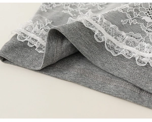 Detailed close-up of grey knitted fabric with delicate white floral lace trim on the hem