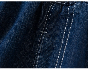 Détail du tissu denim bleu foncé avec des doubles surpiqûres blanches et une texture sergée