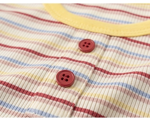 Detail of colorful striped cotton knit top featuring red buttons and ribbed fabric