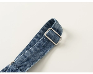 Detail of blue denim overalls strap featuring a high-quality silver metal adjustment buckle
