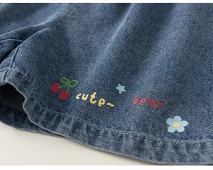 Detail of girls denim shorts featuring cute embroidered cherries and bear typography