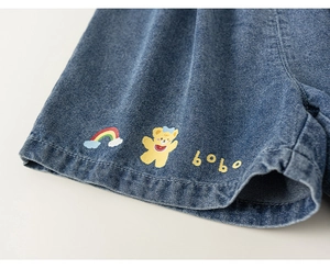 Close-up of kids denim shorts with cute rainbow and yellow bear cartoon prints