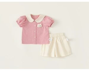 Detail of girls summer set featuring red checkered shirt with a cat patch and white shorts