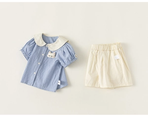 Detail of girls summer set featuring a blue plaid shirt with Peter Pan collar and shorts