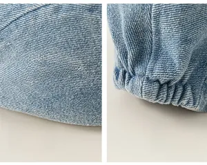 Detail of light blue denim beret showing white embroidery and elastic band adjustability