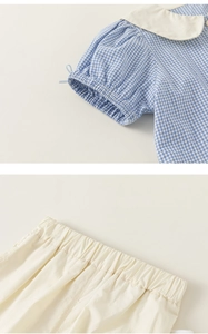 Close-up of blue plaid puff sleeves and elastic waistband on a cotton girl's outfit