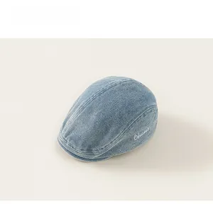 Detailed close-up of light blue denim flat cap with white Chater letter embroidery