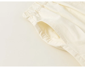 Detail of elastic waist and side pocket on off-white cotton kids shorts in macro view