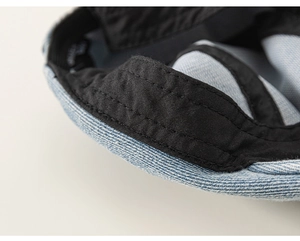Detail view of denim beret hat showing black inner lining and reinforced stitching