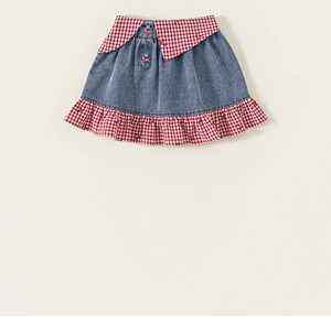 Détail d'une jupe en jean pour fille avec volants vichy rouges et appliqué cerise